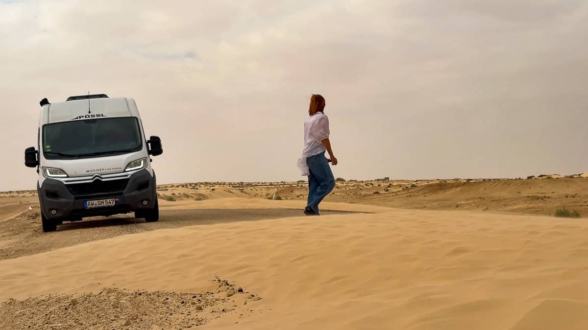 Sand on road woman by campervan on sand covered road in the sahara